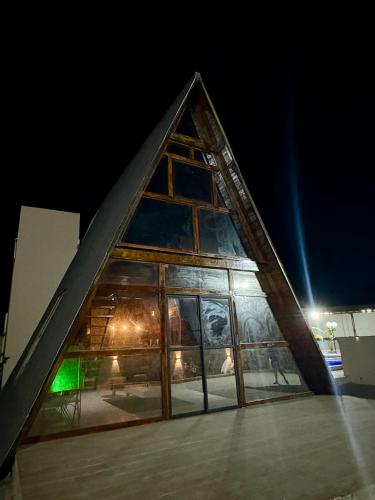 a pyramidangularangular building with glass windows at night at Chalé da Serra in Araruna