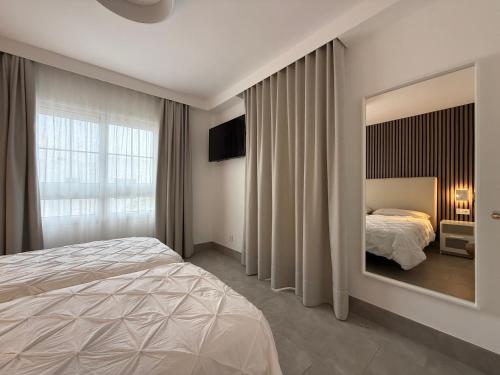Un dormitorio con una cama y un espejo grande. en Izaro Apartamento Atico de Lujo cerca de Playa Dorada, en Playa Blanca
