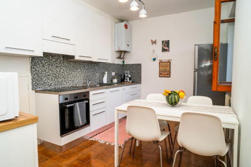 a kitchen with white cabinets and a table and chairs at Casa Il Tramonto Sunset house in Gualdo Cattaneo