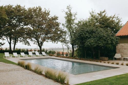 a swimming pool with white chairs and trees at Casa da Fonte de Cima in Celorico de Basto