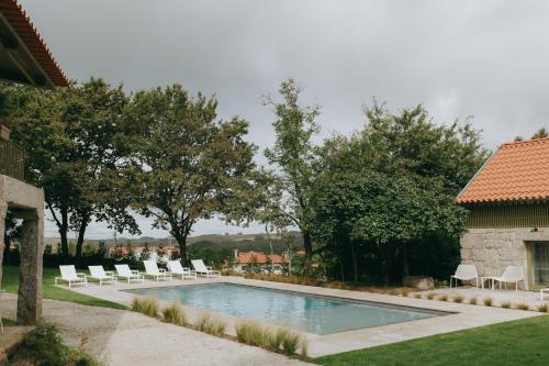 a swimming pool with white lounge chairs next to a house at Casa da Fonte de Cima in Celorico de Basto
