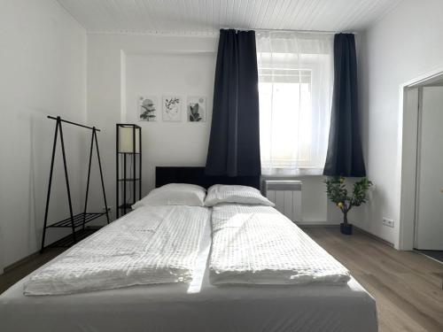 ビーレフェルトにあるModern studio for 2 - Central I Parking I WiFiの寝室にある白いシーツと枕が置かれたベッド