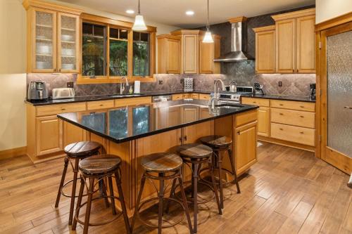 a kitchen with wooden cabinets and a large island with bar stools at Whispering Pines Escape in Suncadia- Hot Tub, BBQ, Firepit, Fully Equipped Kitchen, Smart TVs, Hi-speed Wi-Fi in Roslyn