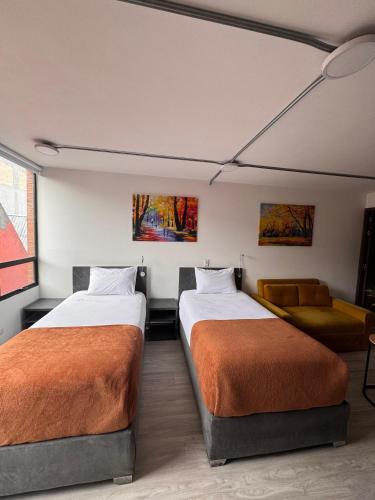 a room with two beds and a couch at Toscana LOFT - Apartasuites in Bogotá