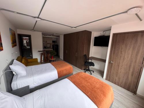 a hotel room with two beds and a television at Toscana LOFT - Apartasuites in Bogotá