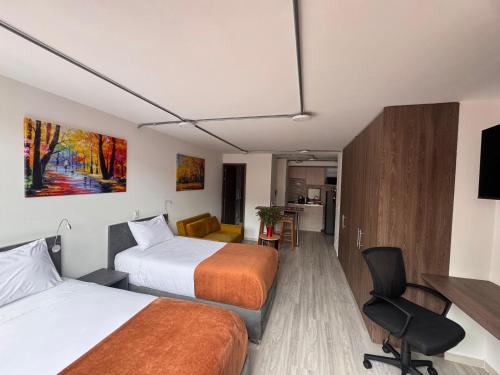 a hotel room with two beds and a desk at Toscana LOFT - Apartasuites in Bogotá