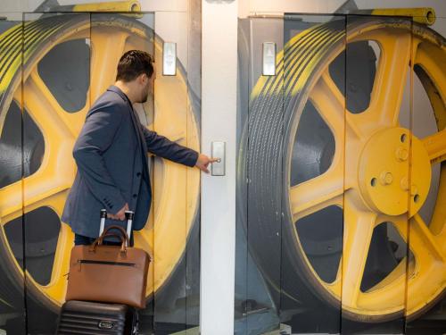 a man pulling a suitcase in front of a train at ibis Besançon Centre la City in Besançon