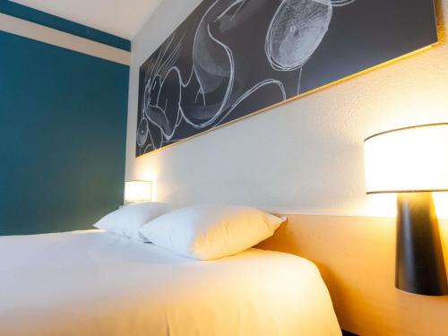 a bedroom with a bed with two lamps on it at ibis Besançon Centre la City in Besançon