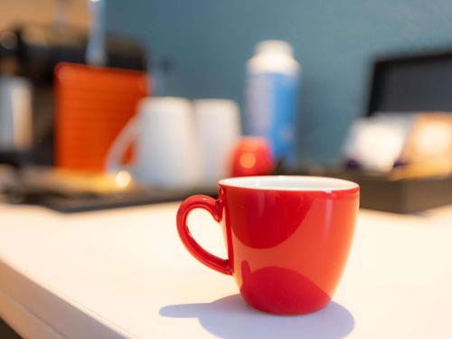 a red coffee cup sitting on a counter at ibis Besançon Centre la City in Besançon
