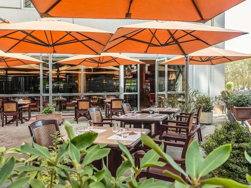 a restaurant with tables and chairs with umbrellas at ibis Besançon Centre la City in Besançon