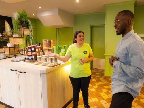a man and a woman standing at a counter at ibis Besançon Centre la City in Besançon