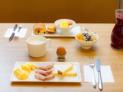 a table with two plates of breakfast foods and eggs at ibis Besançon Centre la City in Besançon
