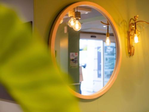 a mirror on a wall with lights in a room at ibis Besançon Centre la City in Besançon