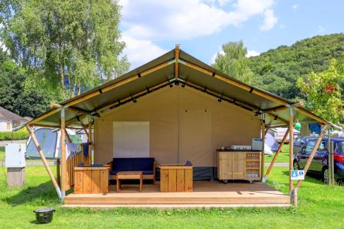 a tent with a bench and a table in a field at Camping Floreal La Roche-en-Ardenne in La Roche-en-Ardenne