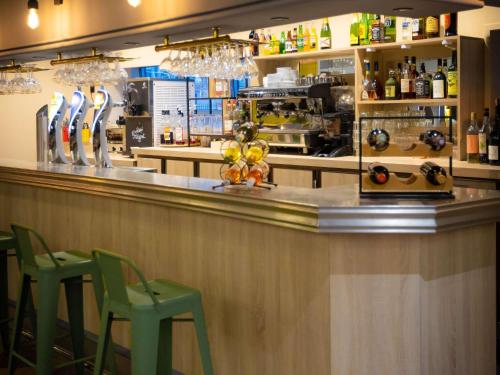 a bar with two green chairs and a counter at ibis Besançon Centre la City in Besançon