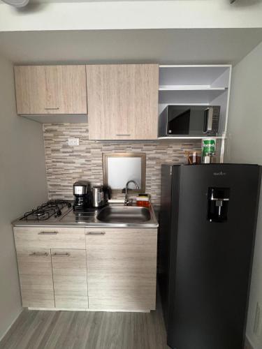 a kitchen with a sink and a black refrigerator at Toscana LOFT - Apartasuites in Bogotá
