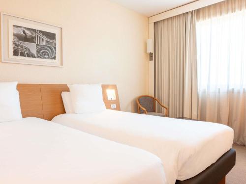 a hotel room with two beds and a window at Novotel Roma Est in Rome