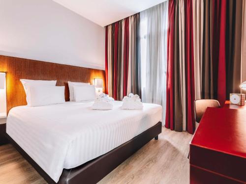 a bedroom with a large white bed and a red curtain at Mercure Roma Piazza Bologna in Rome