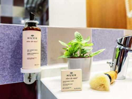 a bathroom counter with a bottle of nue next to a plant at Mercure Roma Piazza Bologna in Rome