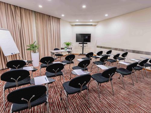 a room with chairs and tables and a screen at Mercure Roma Piazza Bologna in Rome