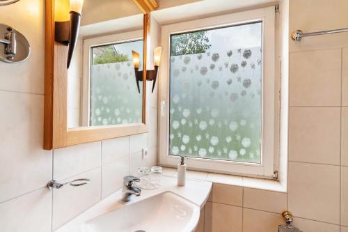 a bathroom with a sink and two windows at Wein- und Klimahotel Bergfriedel in Bühlertal