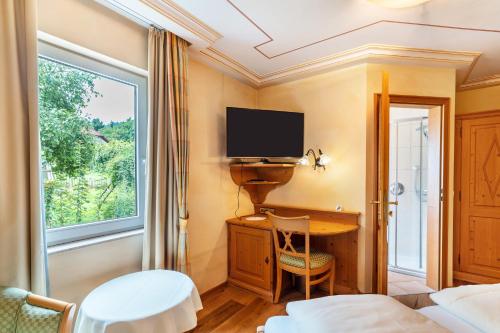 a room with a desk with a tv and a window at Wein- und Klimahotel Bergfriedel in Bühlertal