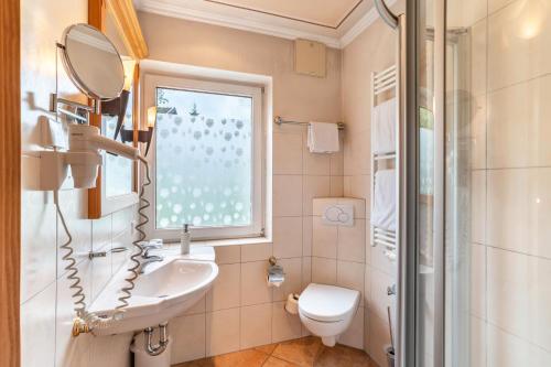 a bathroom with a sink and a toilet and a window at Wein- und Klimahotel Bergfriedel in Bühlertal