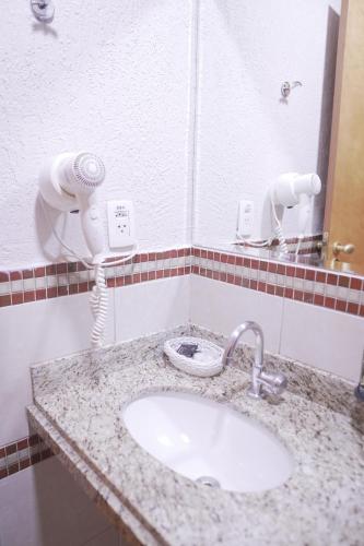 a bathroom counter with a sink and a phone at Castelo Inn Hotel in Goiânia