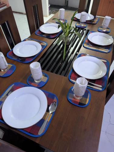 a wooden table with white plates and glasses on it at Sea Breeze Rest in Talalla