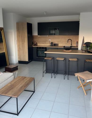 a kitchen with black cabinets and a white tile floor at Appartement proche mer in Le Muy