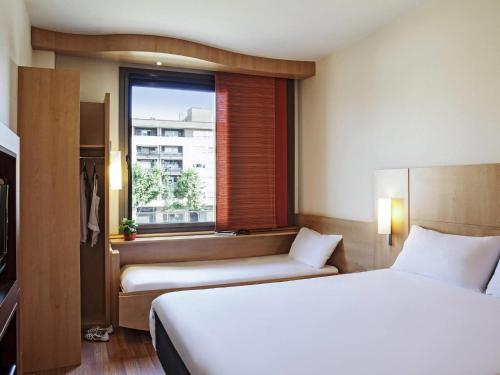 a hotel room with two beds and a window at Ibis Barcelona Mollet in Mollet del Vallès