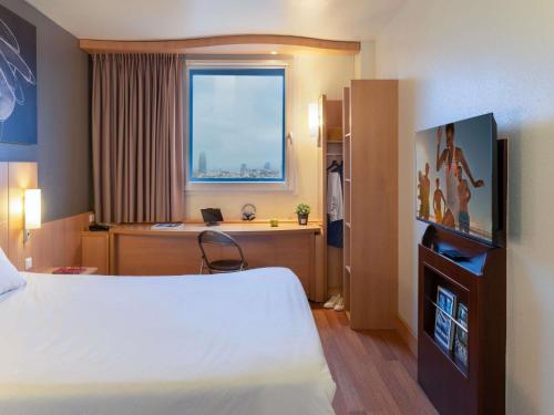 a hotel room with a bed and a desk and a window at Ibis Barcelona Meridiana in Barcelona