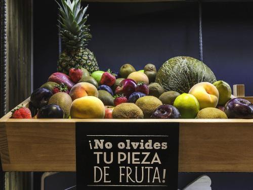 a pile of fruit on a table with a sign at Ibis Barcelona Mollet in Mollet del Vallès