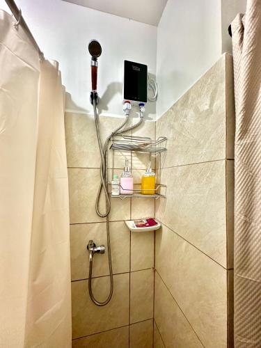 a bathroom with a shower with a tv on the wall at Driftwood Nook in Dauis