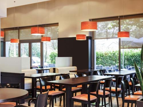 a dining room with tables and chairs and windows at Ibis Barcelona Mollet in Mollet del Vallès