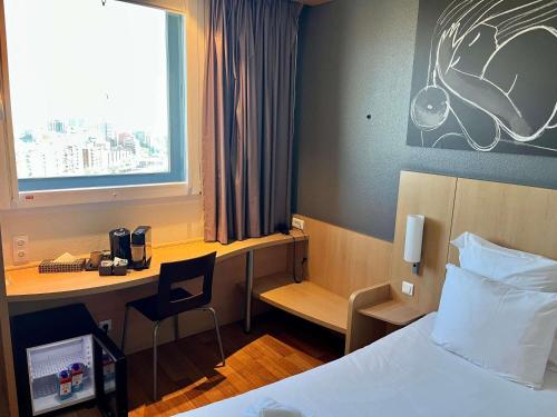a hotel room with a bed and a desk and a window at Ibis Barcelona Meridiana in Barcelona