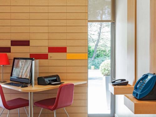 an office with a desk with a computer and red chairs at Ibis Barcelona Mollet in Mollet del Vallès