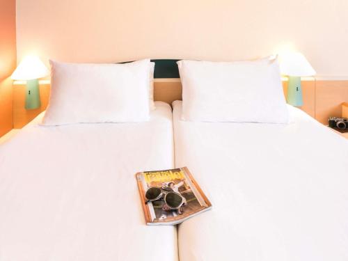 two beds with a magazine sitting on top of them at Ibis Jerez De La Frontera Cadiz in Jerez de la Frontera