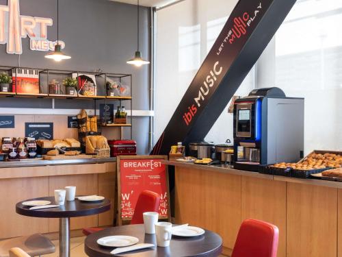 a restaurant with two tables and a counter with food at Ibis Barcelona Meridiana in Barcelona