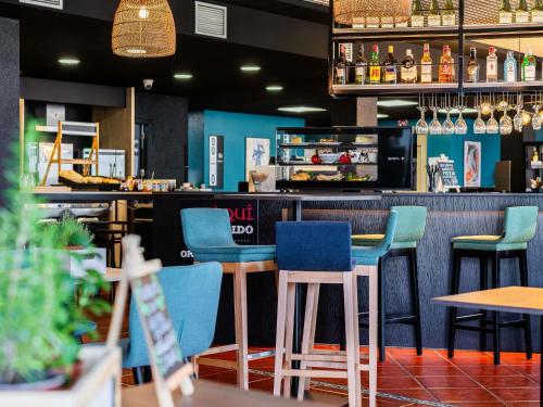 a restaurant with blue chairs and a bar at Ibis Jerez De La Frontera Cadiz in Jerez de la Frontera