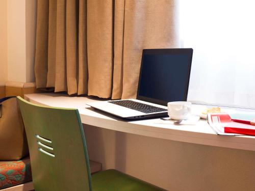 a laptop computer sitting on a desk with a cup of coffee at Ibis Bilbao Barakaldo in Barakaldo