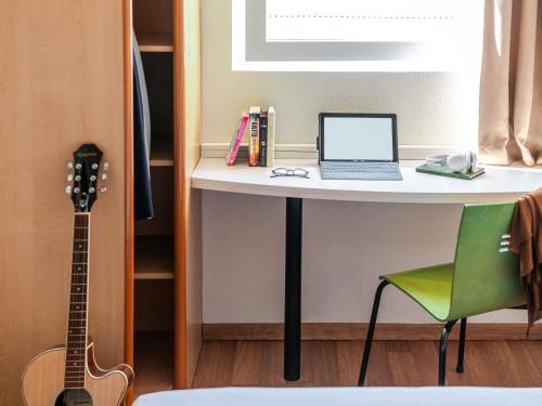 a desk with a laptop computer and a guitar at Ibis Bilbao Barakaldo in Barakaldo