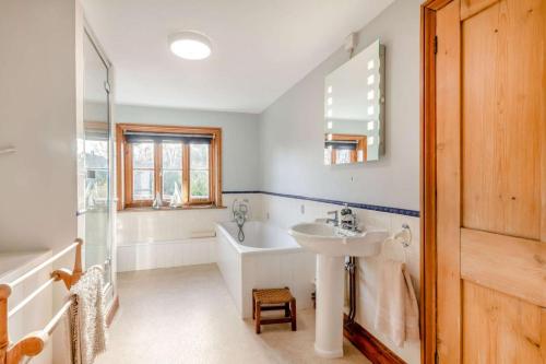 a bathroom with a bath tub and a sink at China Cottage in Weybourne