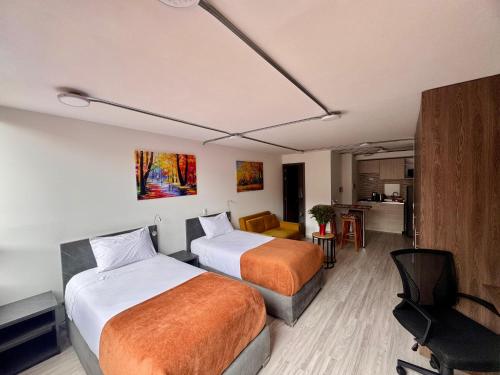 a hotel room with two beds and a desk at Toscana LOFT - Apartasuites in Bogotá