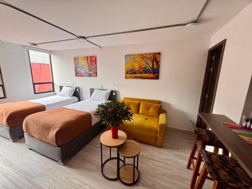 a hotel room with two beds and a couch at Toscana LOFT - Apartasuites in Bogotá