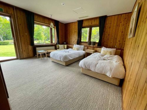 two beds in a room with wooden walls and windows at The Lakehouse at Toyako - Vacation STAY 44251v in Tōya
