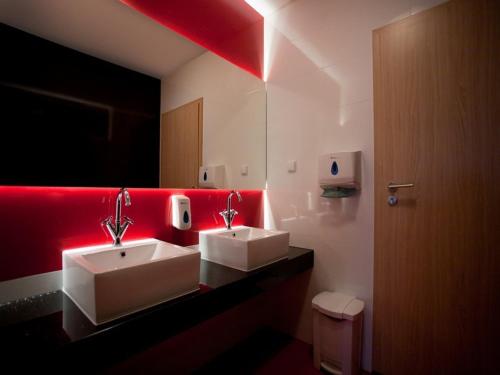 baño con 2 lavabos y pared roja en Hotel Czarna Perła, en Przejazdowo