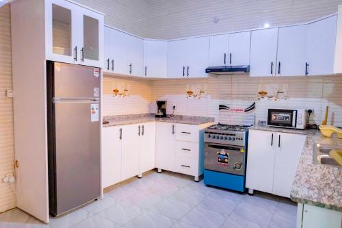 a kitchen with white cabinets and a stainless steel refrigerator at Modern Furnished House in Kabeza in Kigali