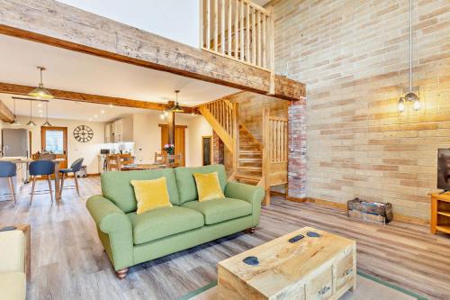 a living room with a green couch and a wooden wall at Abbots Barn in Upwell