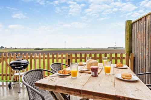 a wooden table with plates of food and glasses of orange juice at Abbots Barn in Upwell